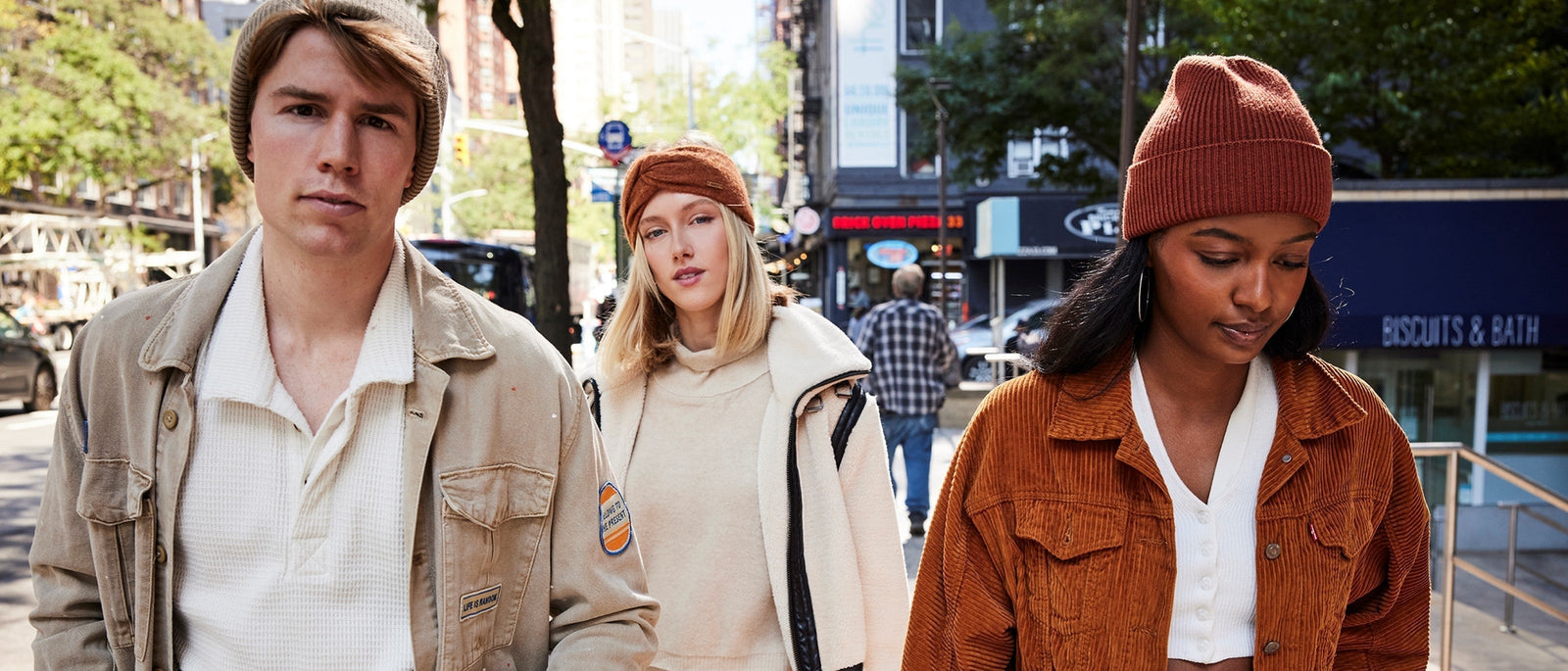 Three stylish young people walking down a busy city street.